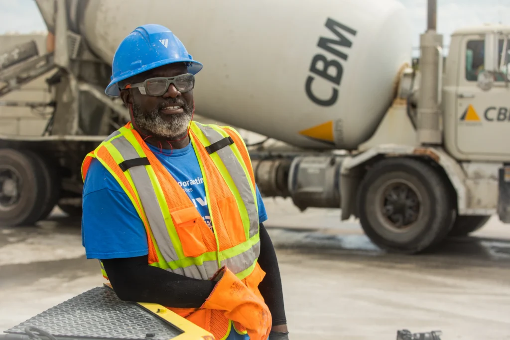 Ready Mix Concrete Capabilities - worker in a hard hat and hi-vis vest beside a CBM ready-mix truck