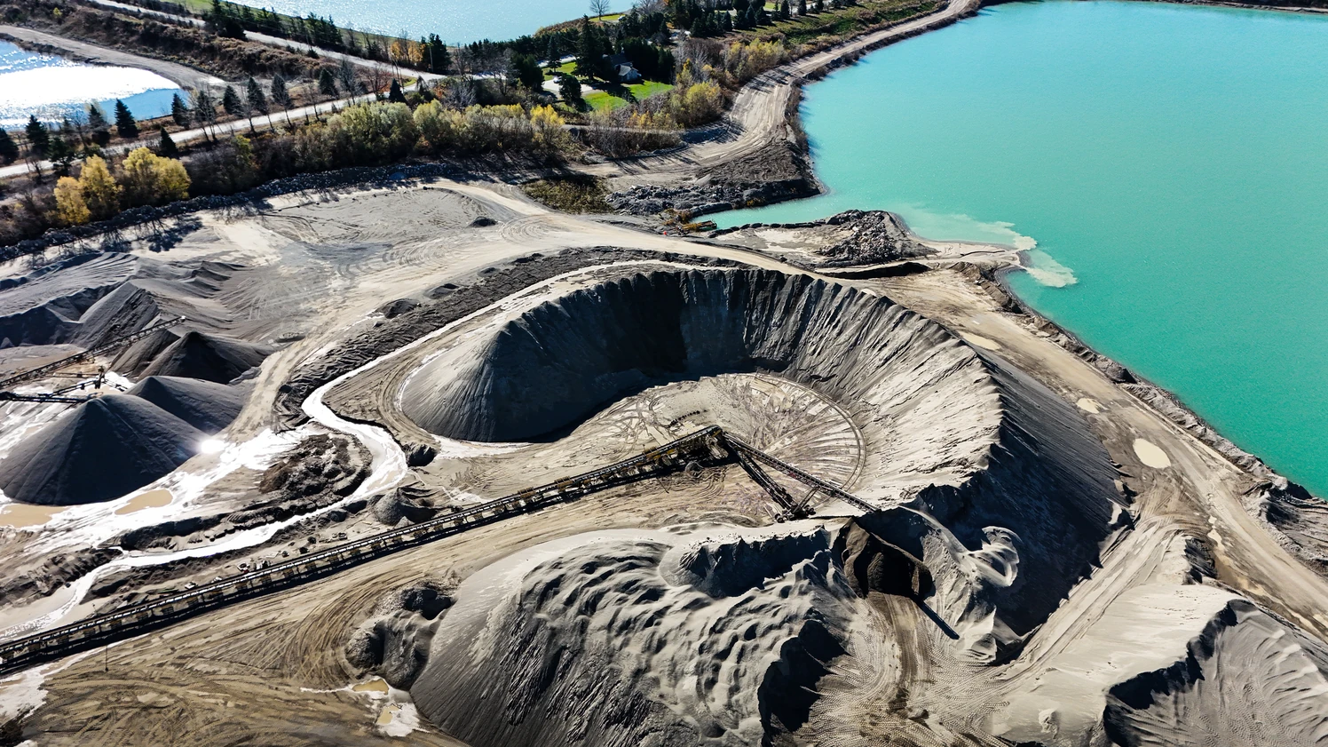 Concrete and Aggregates Supplier in Ontario - aerial view of an aggregate quarry with stockpiles beside turquoise water