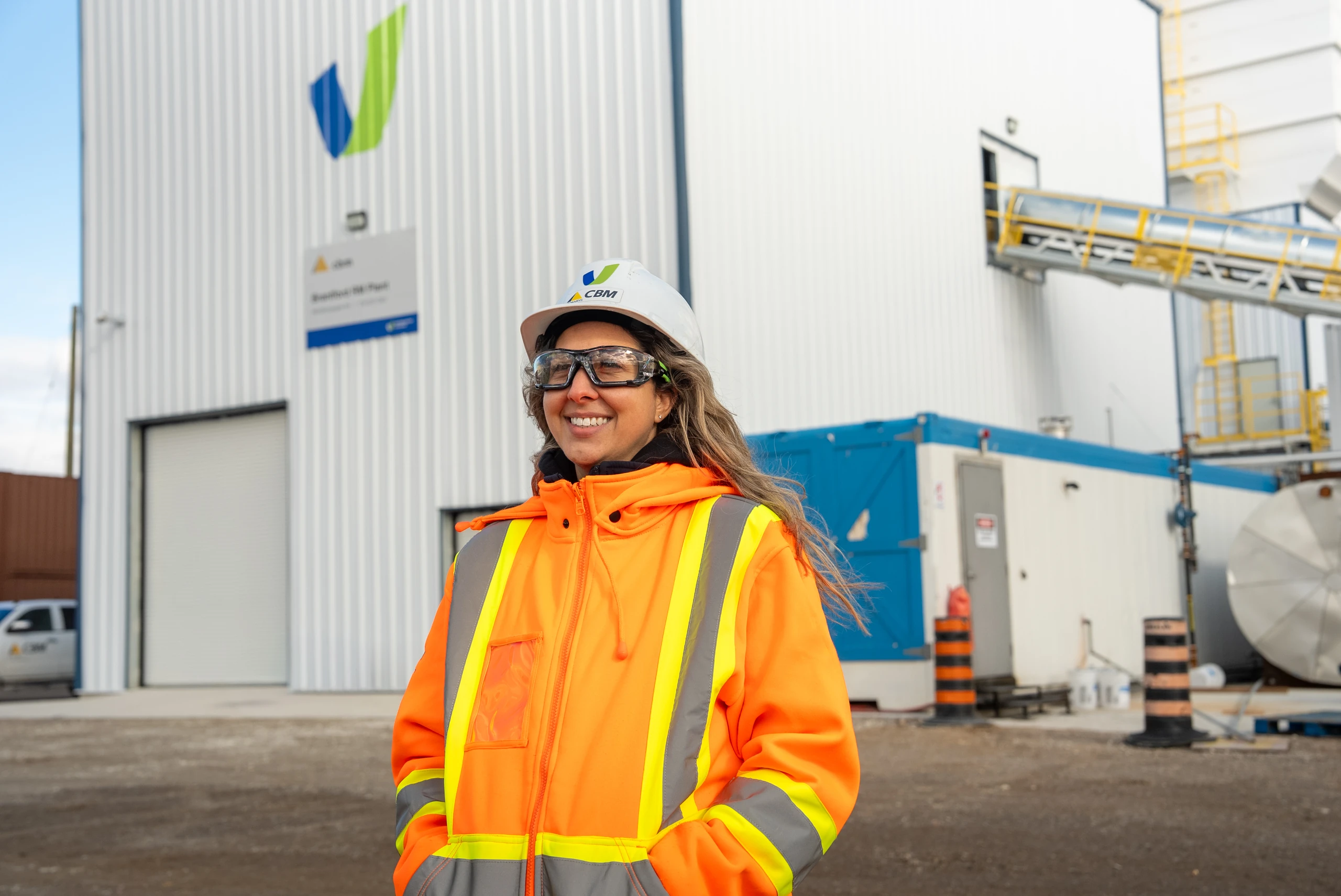 Concrete and Aggregates Supplier in Ontario - smiling CBM employee in a hard hat and hi-vis jacket outside a concrete plant